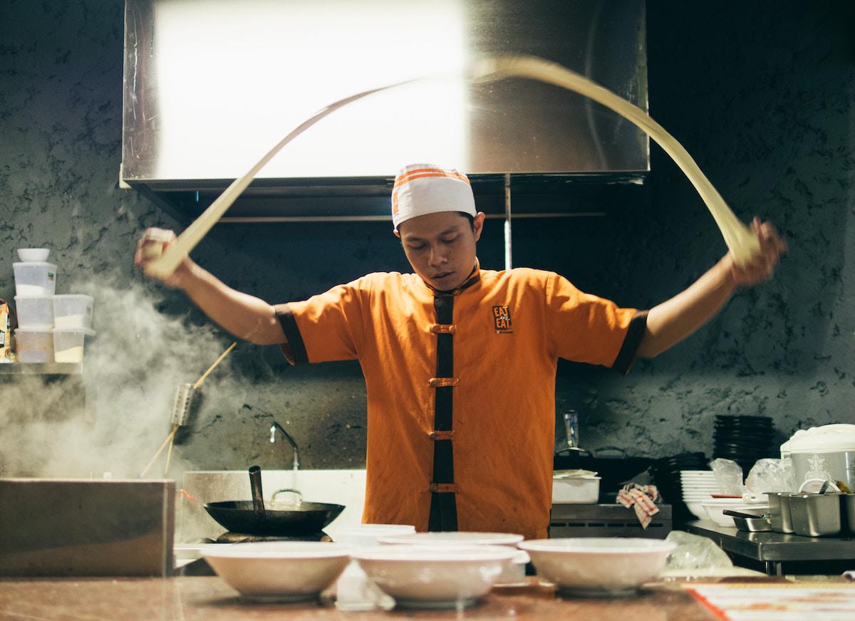 Cook preparing noodles in a kitchen